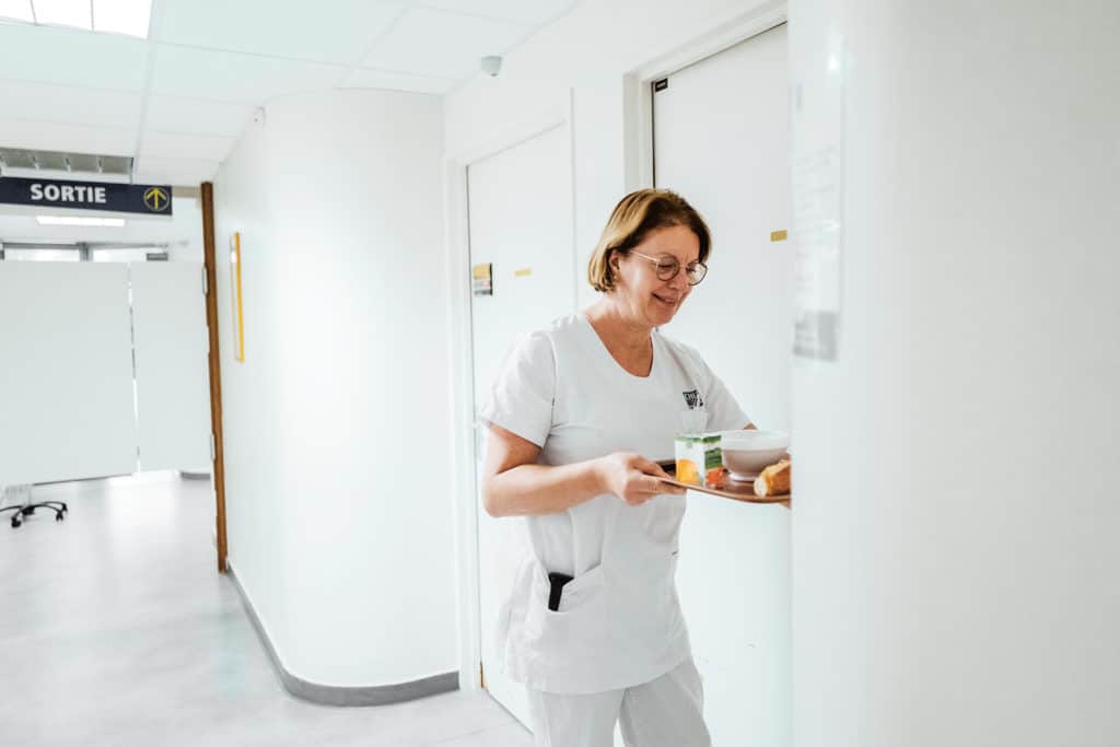 Jeannine apporte un petit déjeuner dans la chambre d’une patiente, le « moment réconfortant », souligne l’aide-soignante.